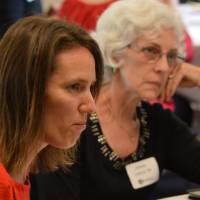 Two alumnae listening to a conversation at a table